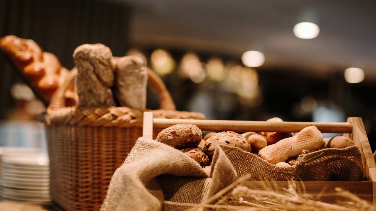 Eine Nahaufnahme von Brot beim Bauernbrunch. Zusehen sind zwei Körbe mit Brot und ein Stapel Teller.