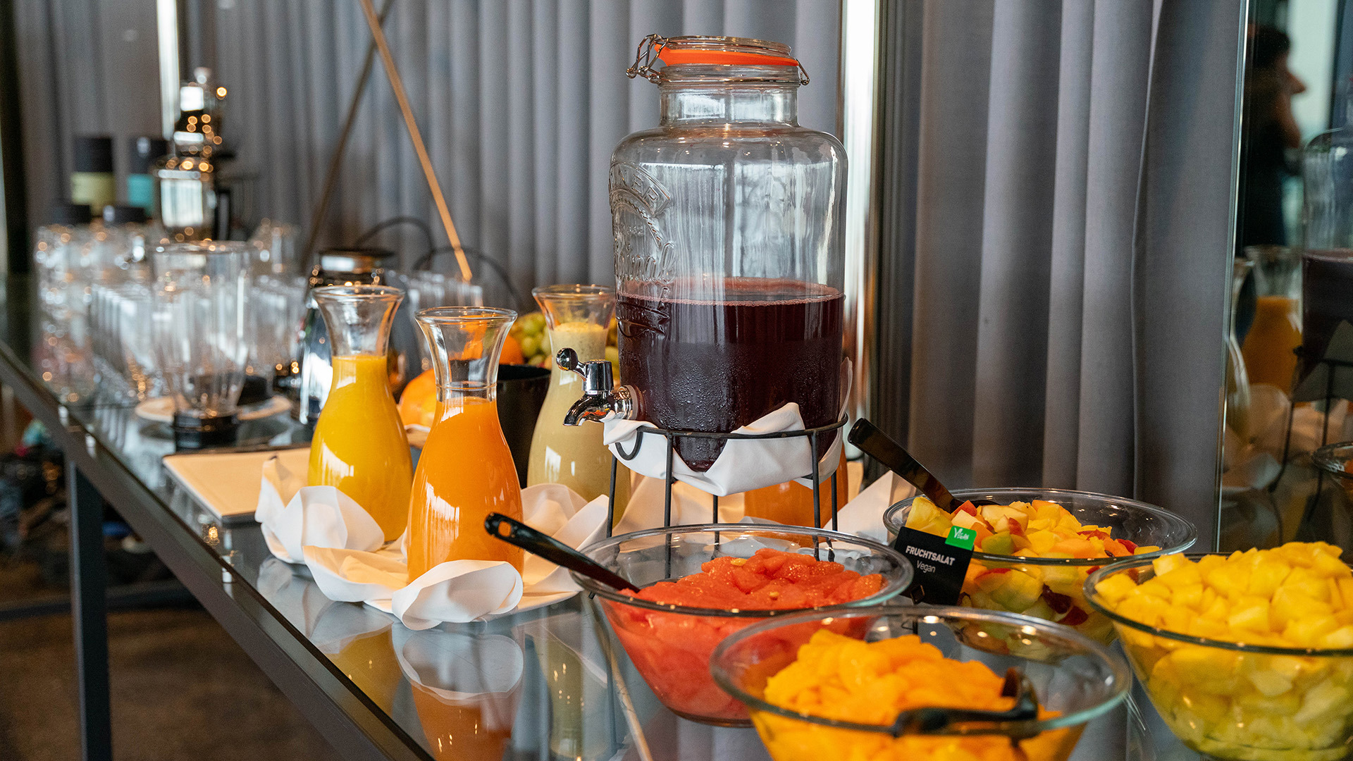 Das Buffet beim Yogabrunch mit Schüsseln mit Früchten, Karaffen mit Säften und vielen Gläsern.