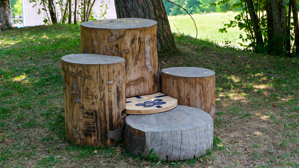 Drei Holzstämme mit einem Schild zum Erlebnisweg «Natur. Und du?»