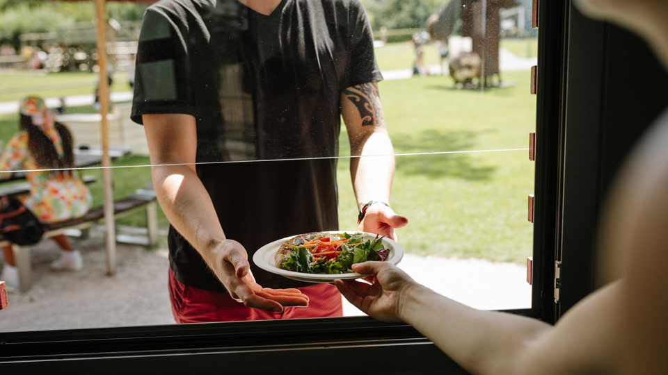 Ein Mann nimmt einen Salat bei der Essensausgabe vom Take-away Stand Bahnhöfli entgegen.
