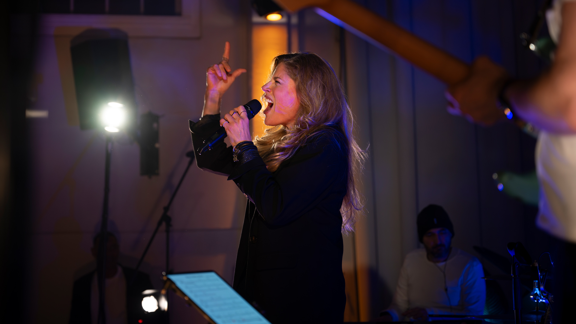 Sängerin auf einer Bühne singt mit gross geöffnetem Mund in ein Mikrophon