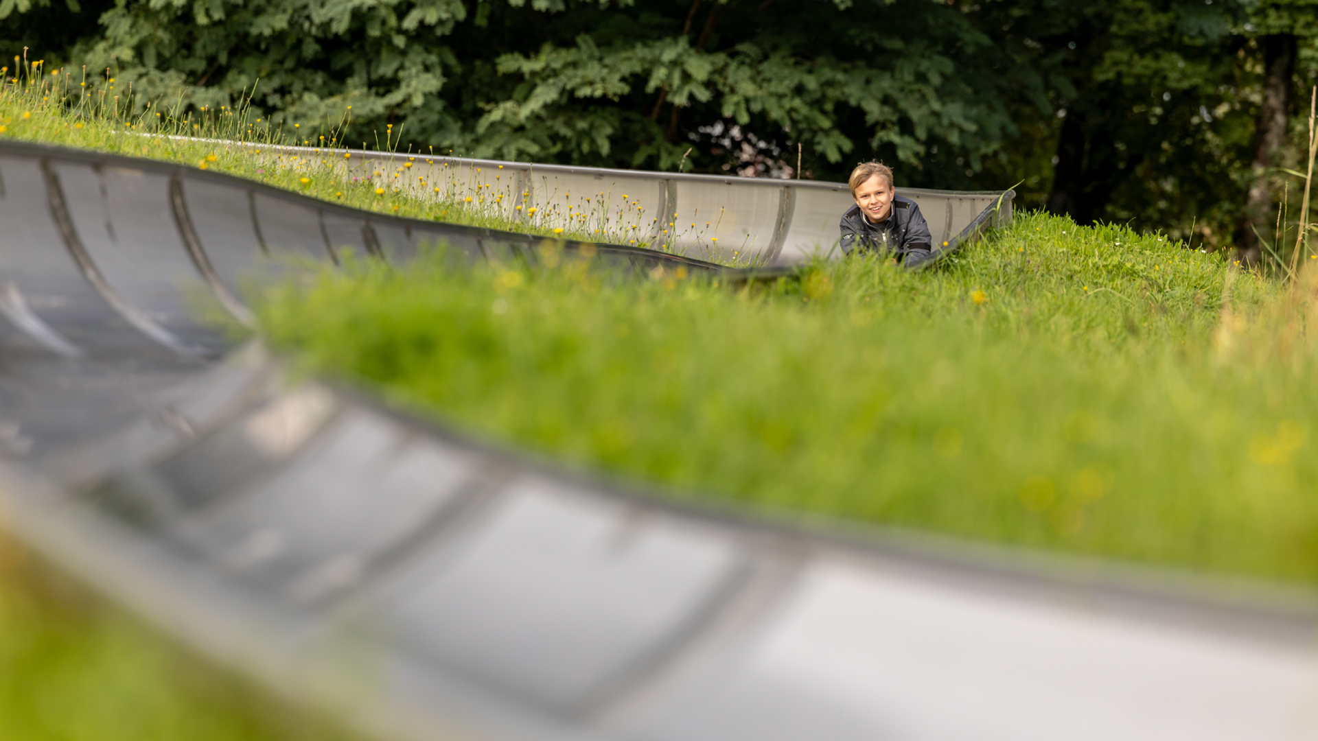 Verschwommene Rodelbahn im Vordergrund, Kind am Rodeln im Hintergrund