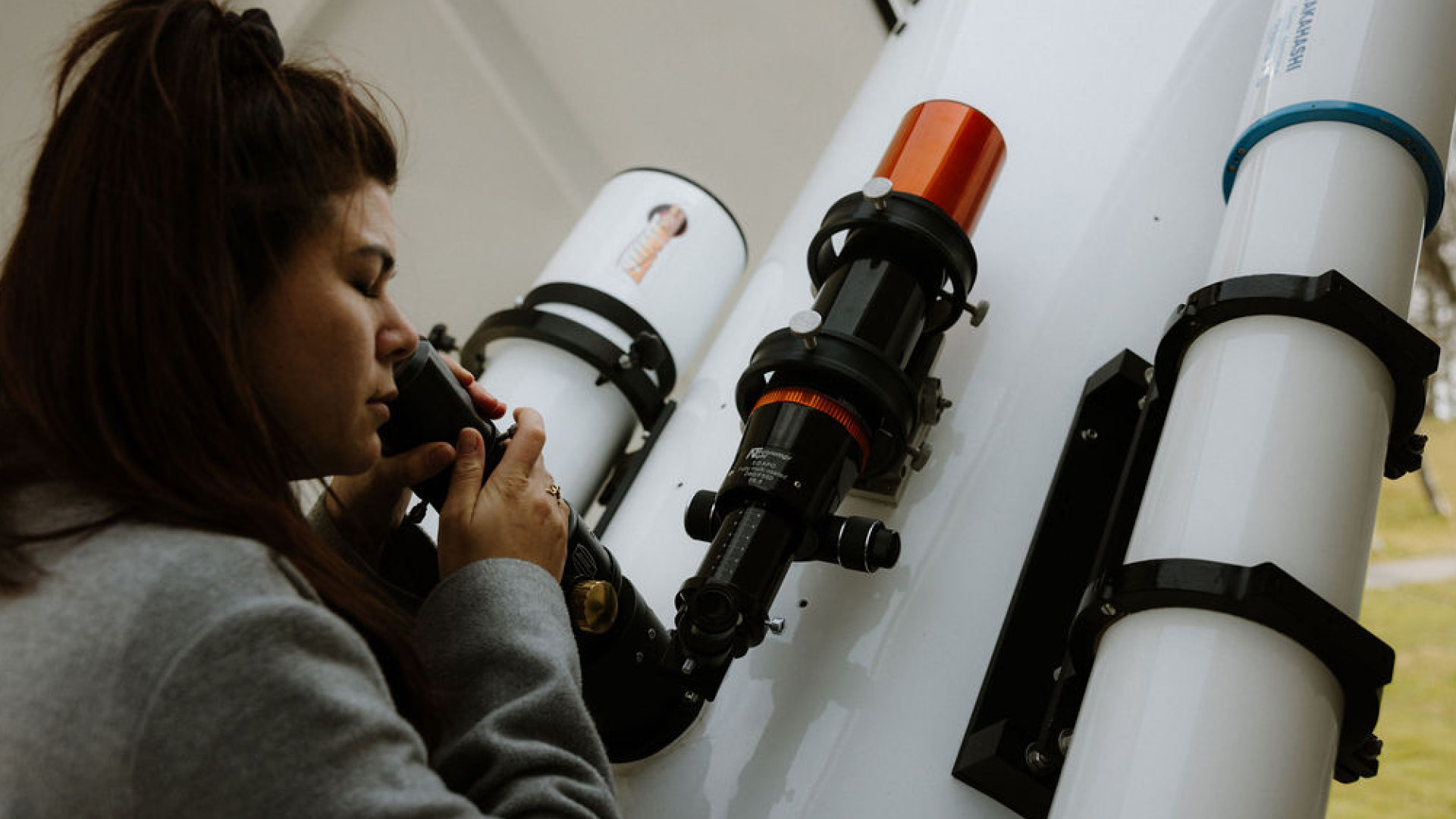 Eine Personen schaut bei tag durch das Teleskop.