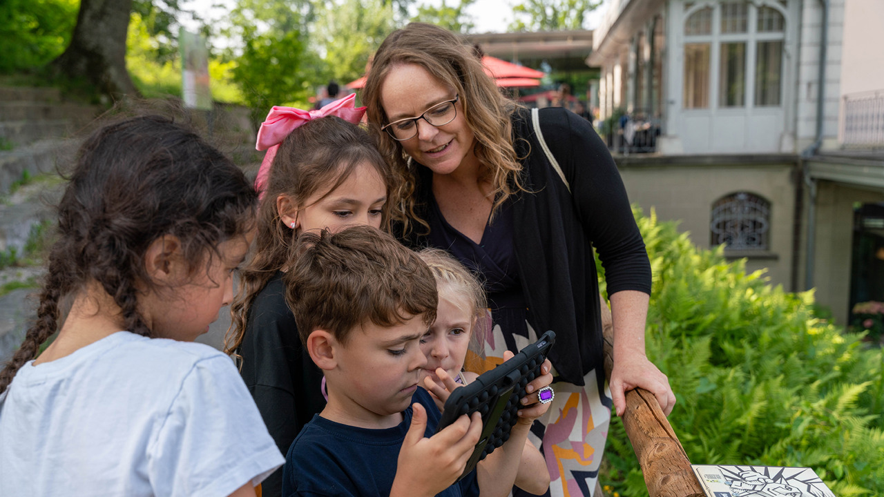 Quatre enfants et une mère regardent tous la même tablette