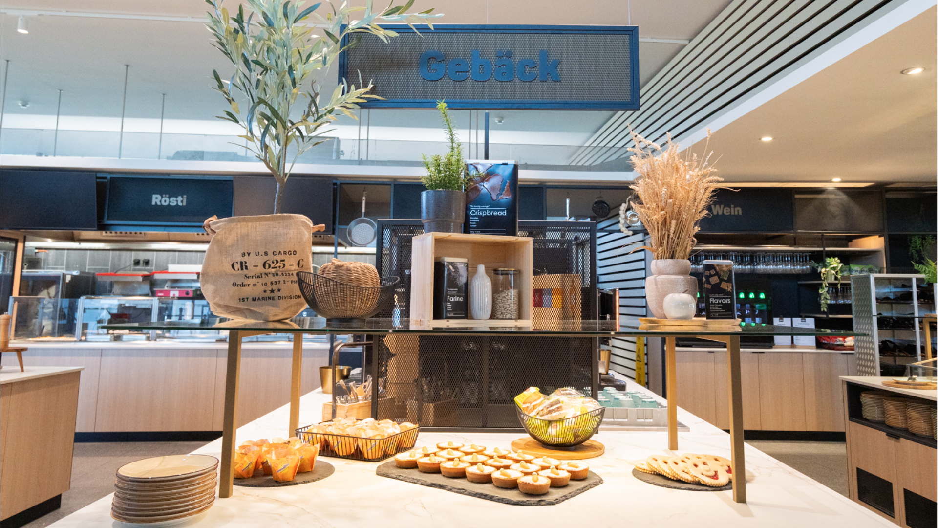 Die Buffetinsel mit Gebäck im Selbstbedienungsrestaurant Huusbüffe. Im Hintergrund sieht man die Röstiausgabe und das Buffet mit dem Wein.