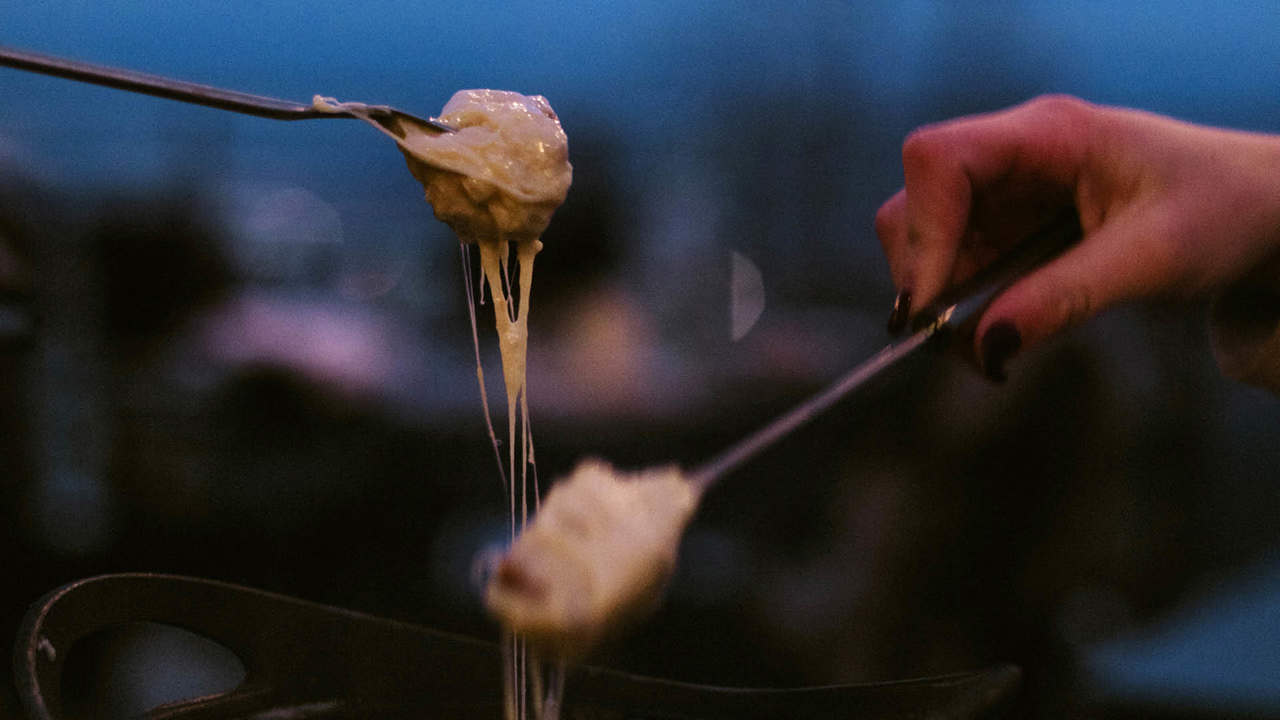 Zwei Personen welche die Gabel auf der Fondue Pfanne nehmen.