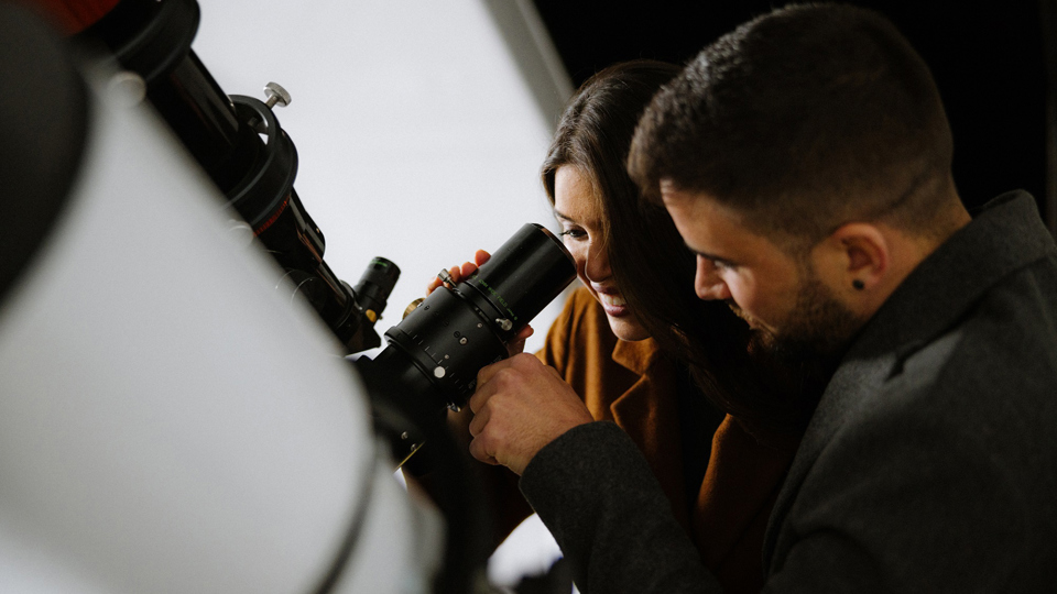 Eine Frau blickt durch das grosse Teleskop in der Gurten-Sternwarte und ein Mann steht nebendran.
