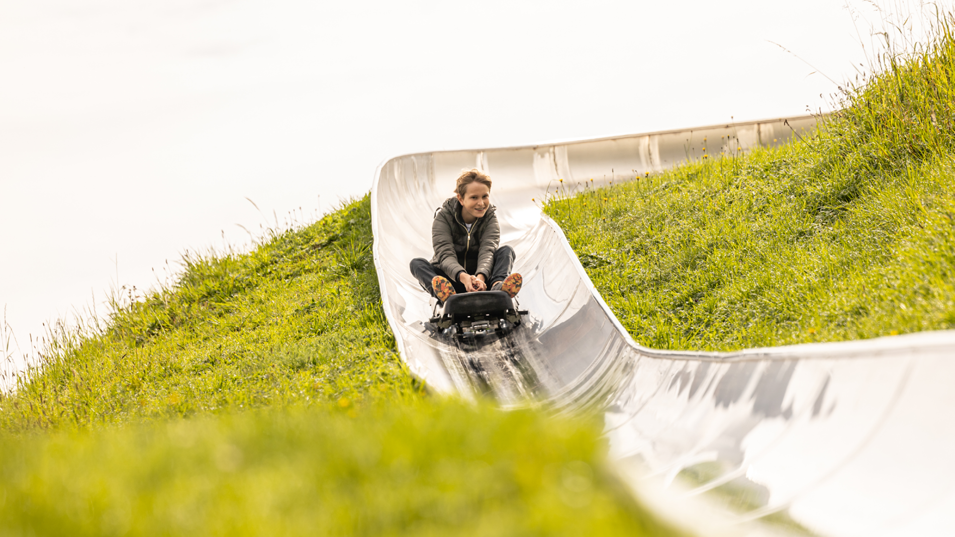 Kind saust nach der Kurve der Rodelbahn gerade hinunter