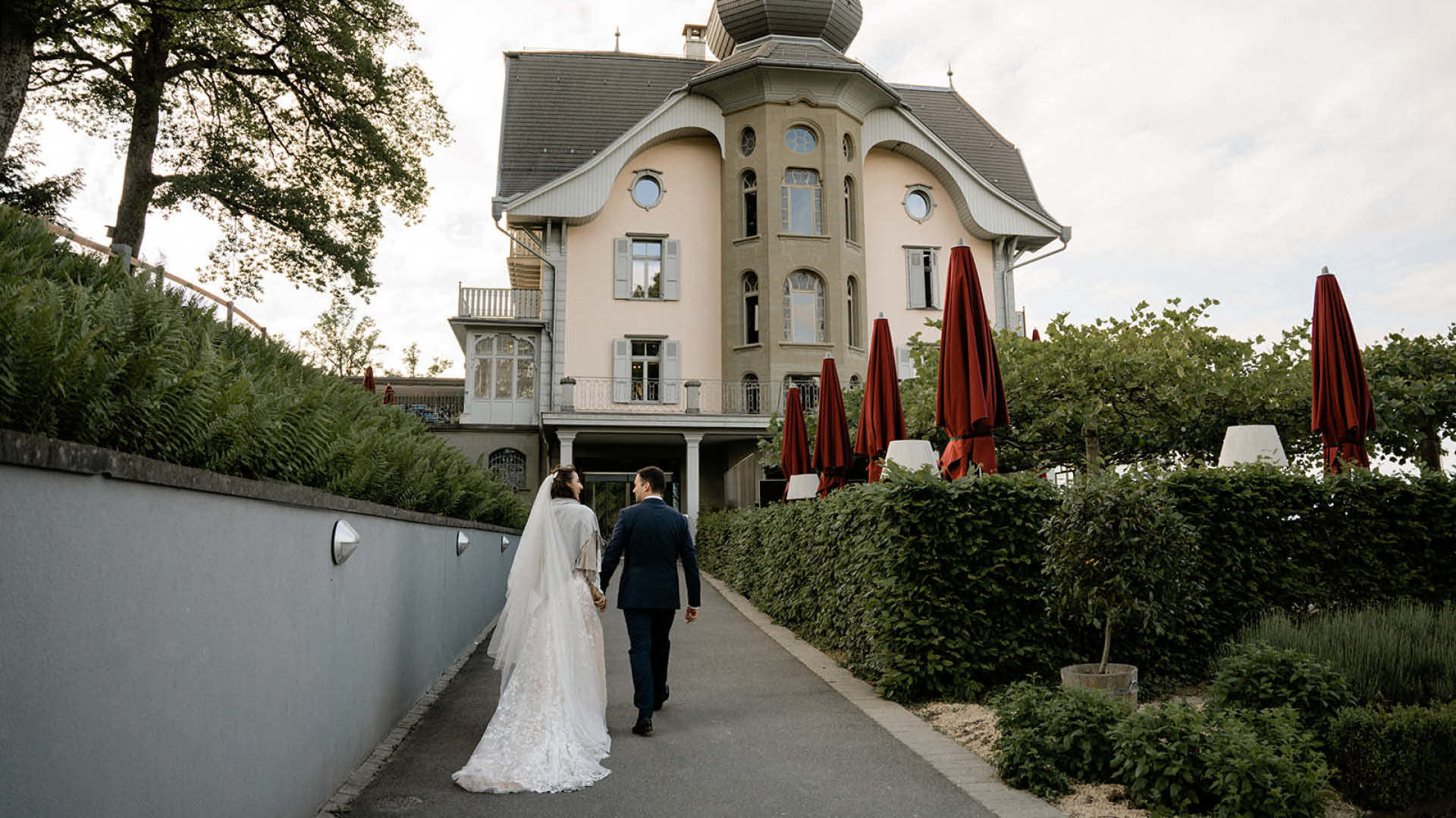 Ein Hochzeitspaar geht in Richtung Kum Gebäude.