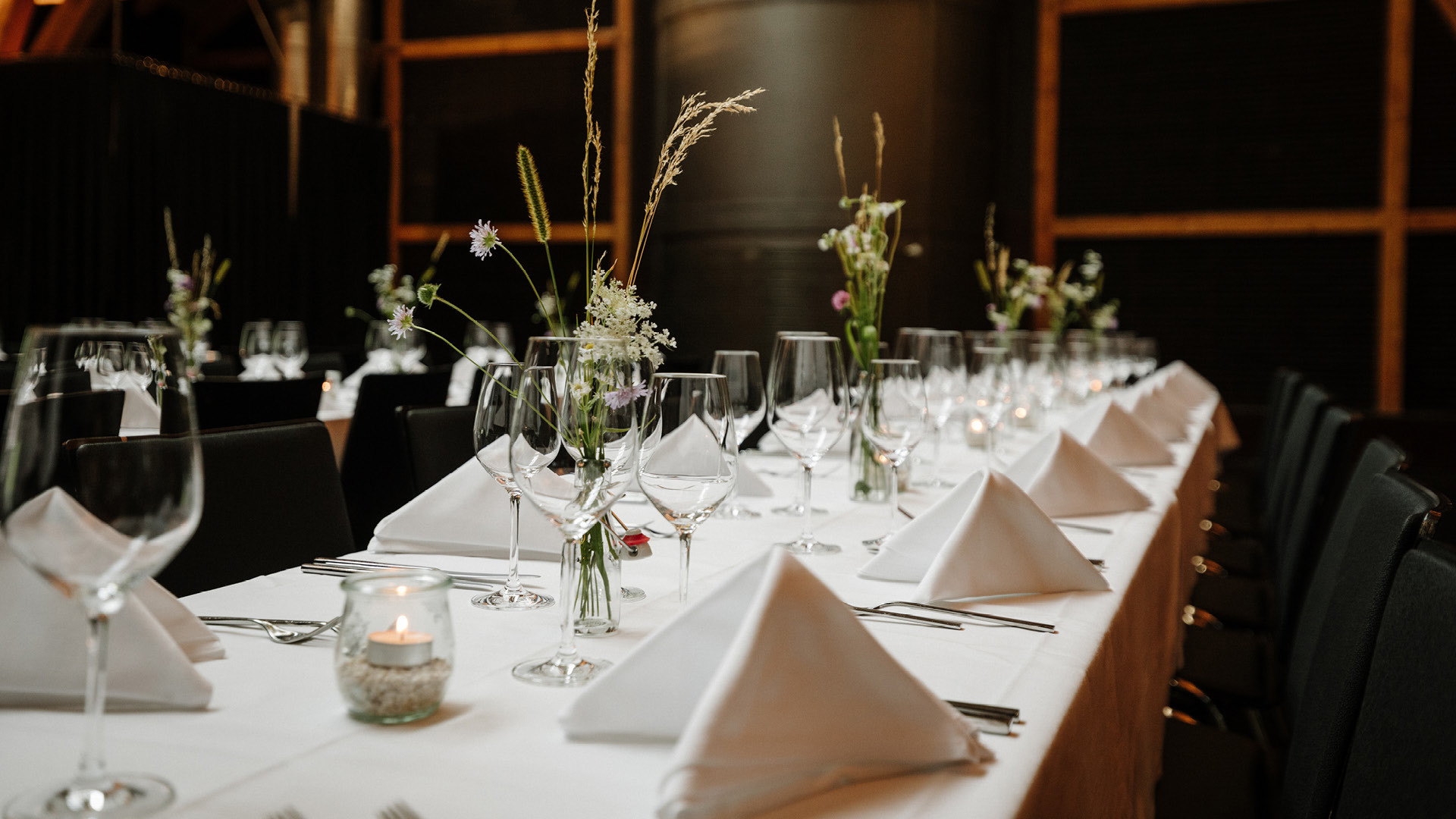 Ein Eventraum schön aufgedeckt mit grünen Blumen.