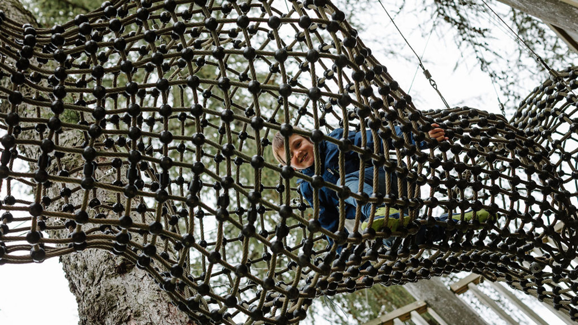 Kind klettert in Klettergerüst aus Seil