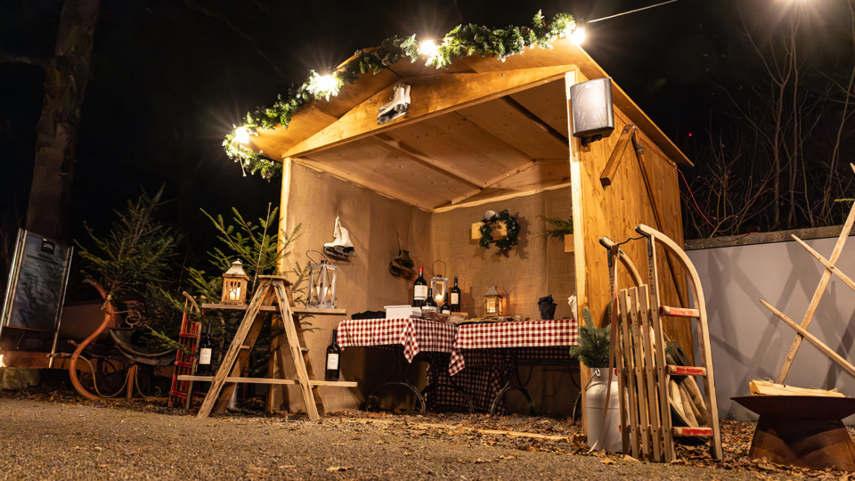 Winterdorf auf dem Gurten mit festlich dekorierter Holzhütte bei Nacht.