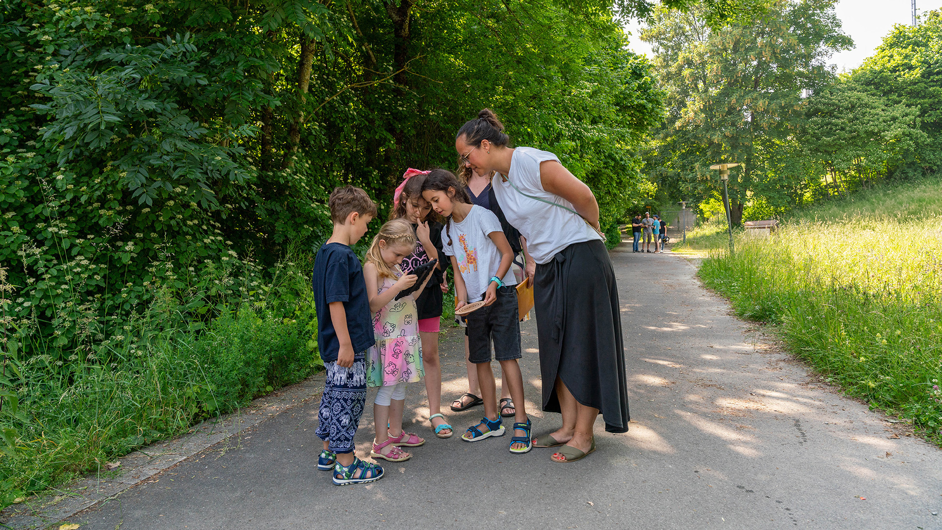 Plusieurs personnes regardent toutes la même tablette lors d'un jeu d'évasion en plein air à Gurten