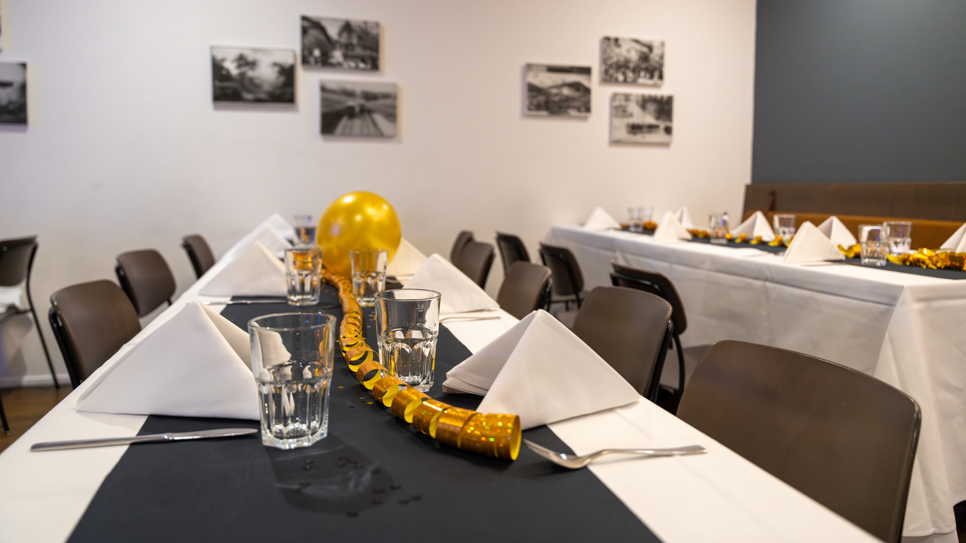 Feierlich gedeckte Tische mit goldenen Luftschlangen und Ballonen im Huusbüffe