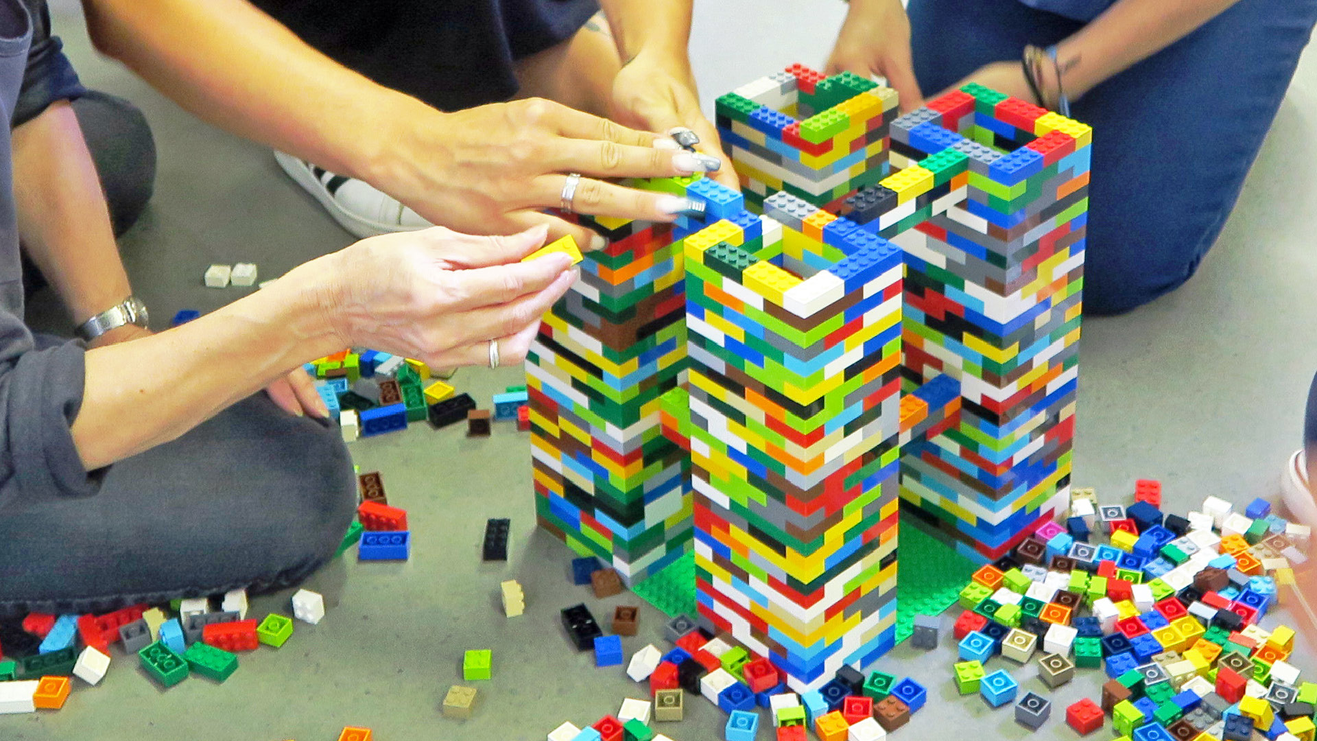 Menschen bauen zusammen einen Legoturm
