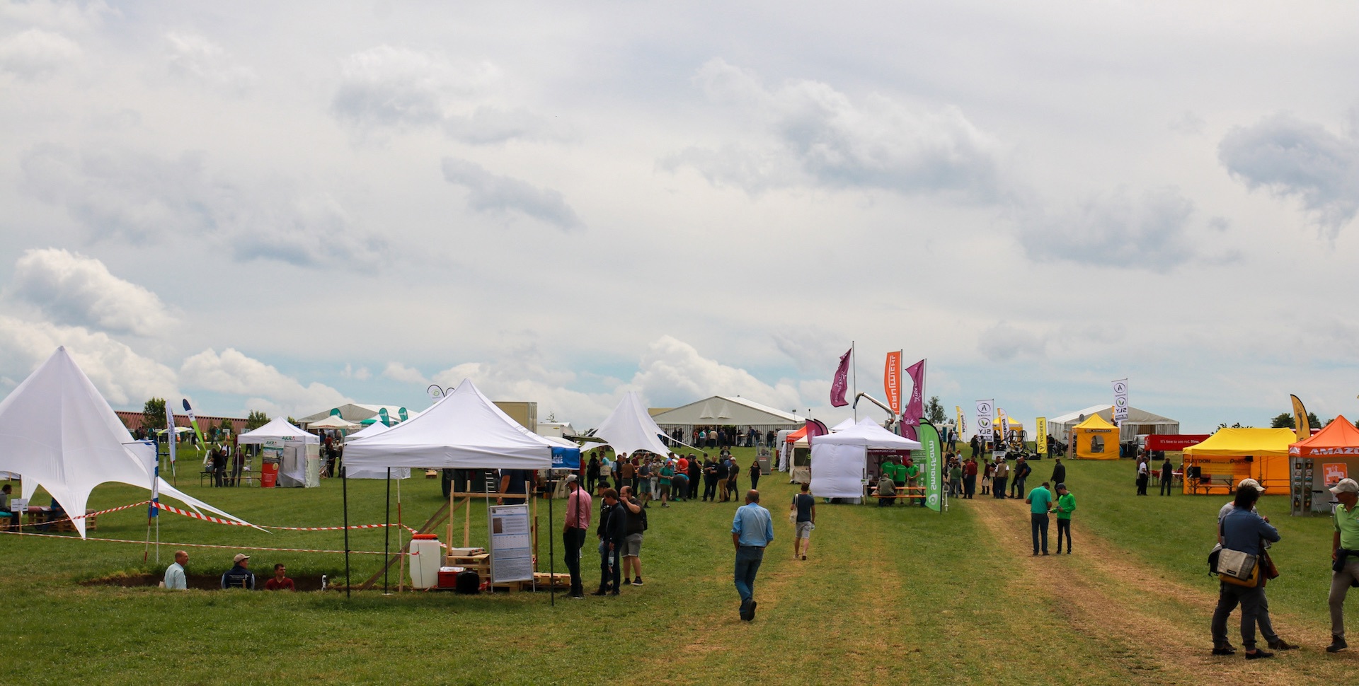 The festival grounds with white tents by Soil Evolution