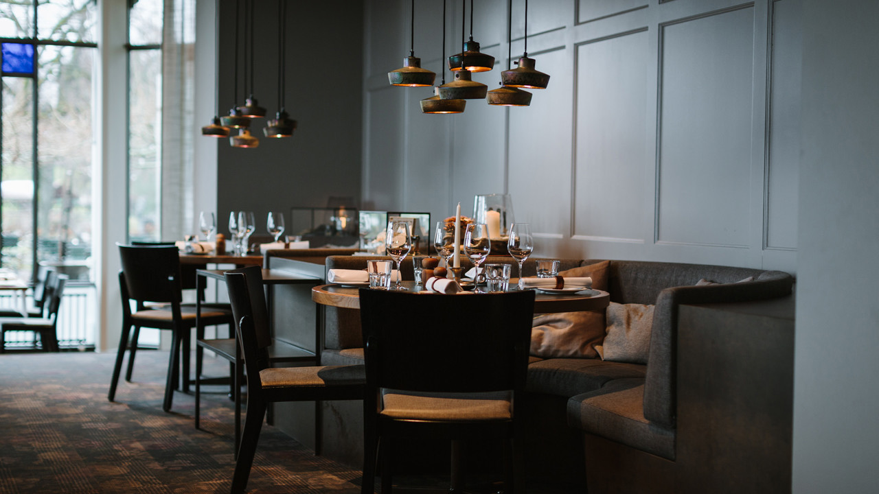 Das Stübli im Restaurant Gurtners. Zwei Tische sind hübsch aufgedeckt und stehen vor einer grauen Wand.