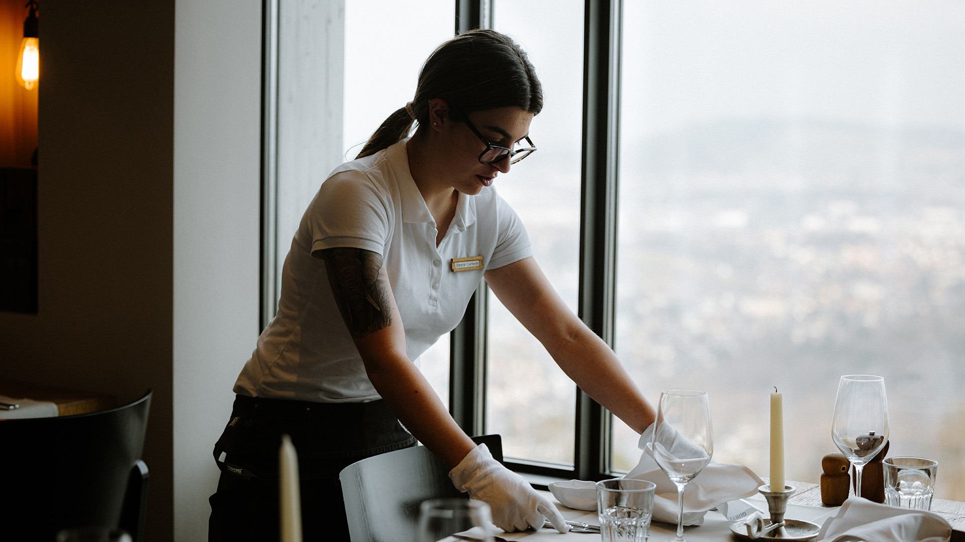 Eine junge Servicemitarbeiterin deckt den Tisch.