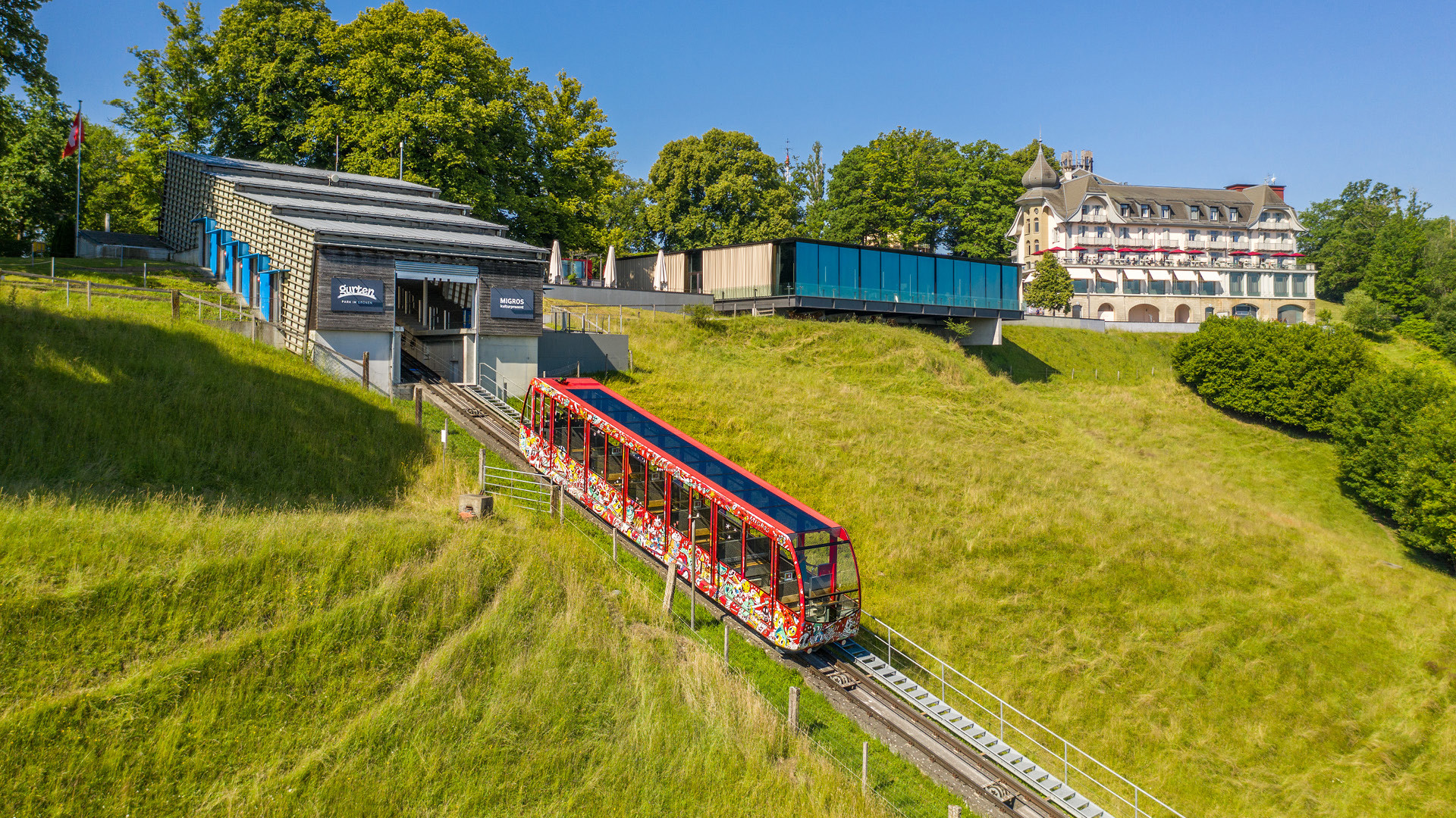 Foto der roten Gurtenbahn, mit Kunst bemalt, vor dem Kulmgebäude