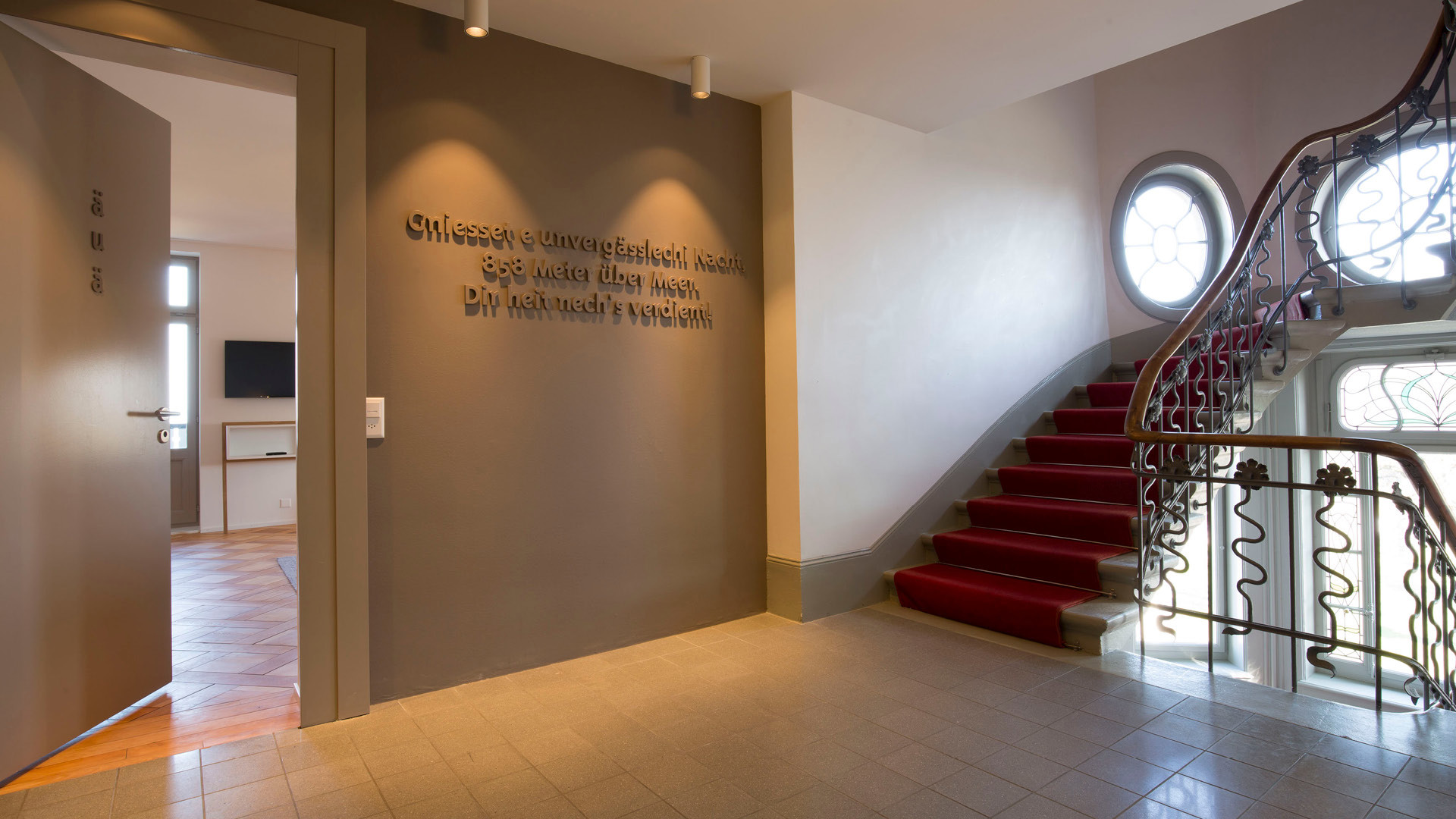 Das Treppenhaus vor dem Zimmer "äuä". Die Treppe hat einen roten Teppich aufgelegt.