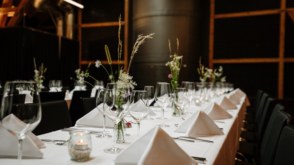 Die Eventlocation Schüür ist festlich bedeckt mit weissen Tischtücher und Servietten.