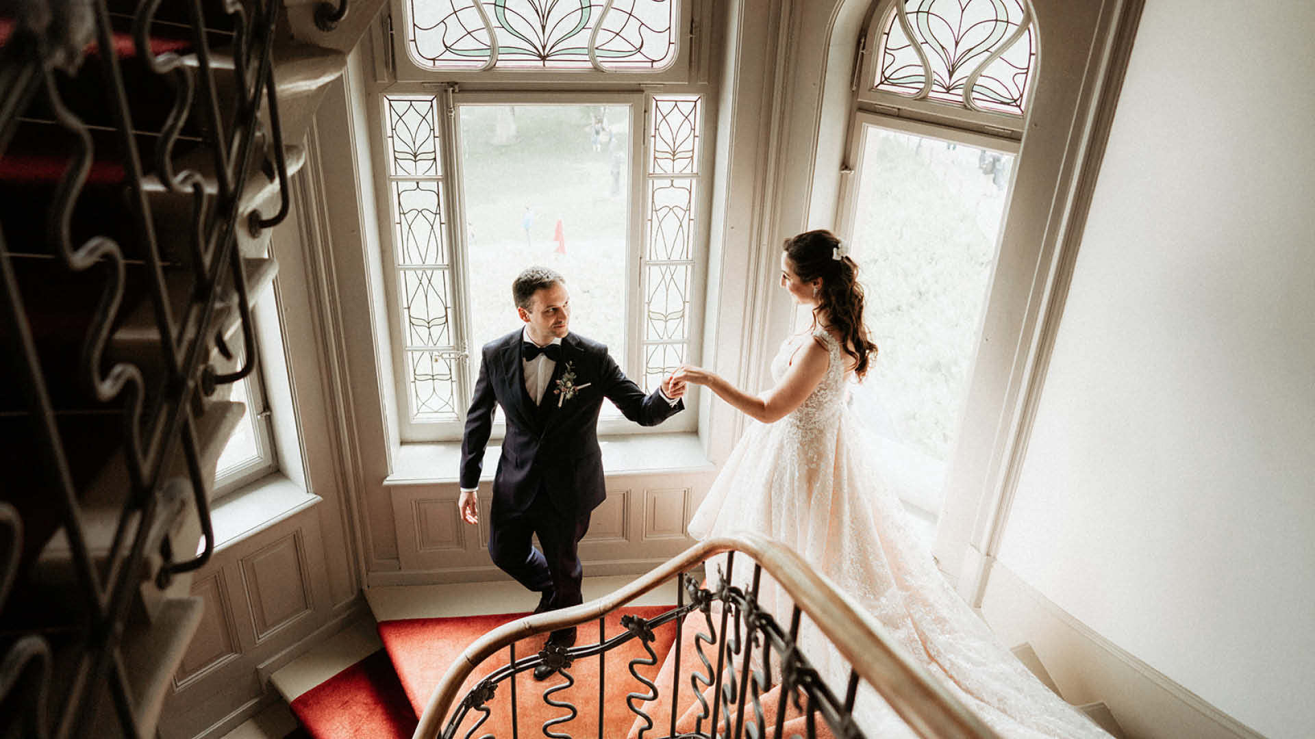 Ein Hochzeitslocation geht Hand in Hand die Treppe hinunter.