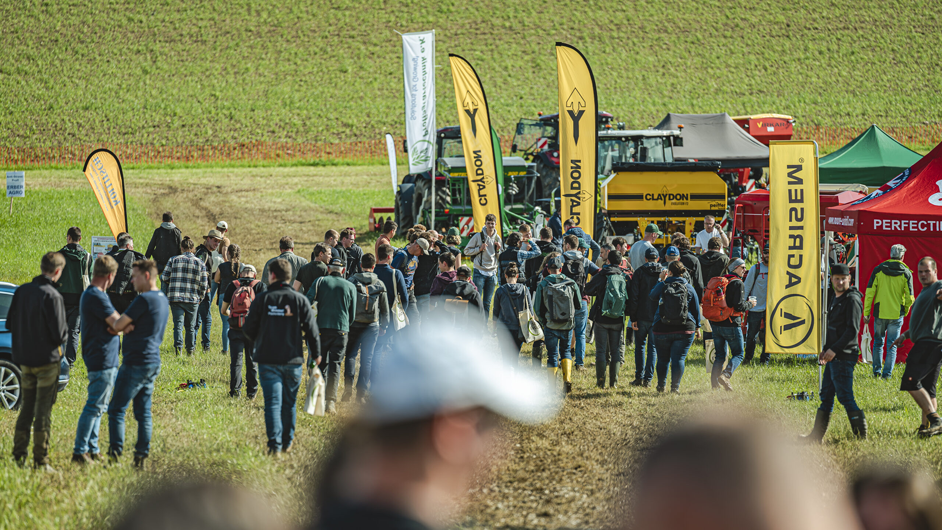 There were many people and farm machines on the large field at the festival grounds