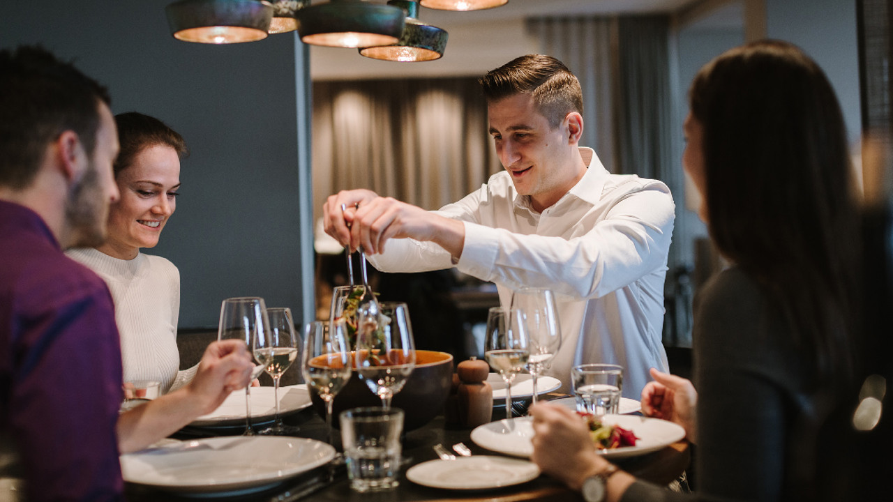 Vier Personen welche an einem Tisch sitzen und gerade Slaat aus der Salatschüssel schöpfen. Sie sitzen im Stübli im Restaurnat Gurtners am Geniesser Montag.