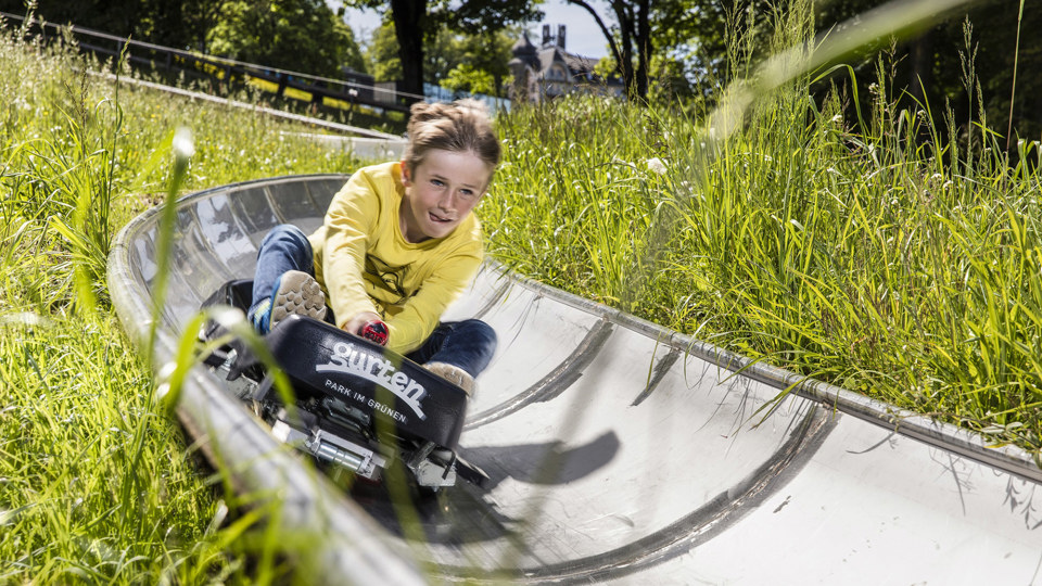 Ein Junge fährt im Sommer die Rodelbahn hinunter