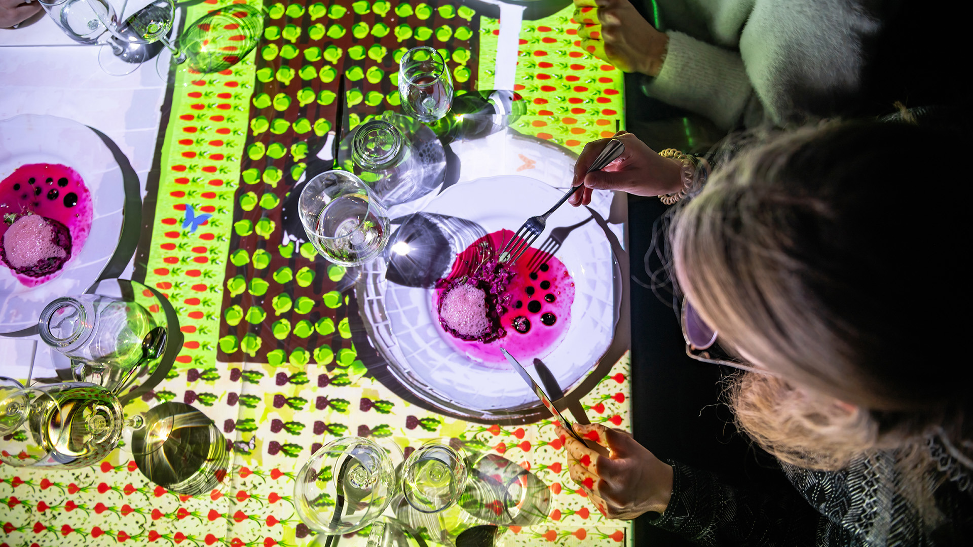 Eine Frau isst an einem Tisch eine Suppe mit immersiver Beleuchtung.