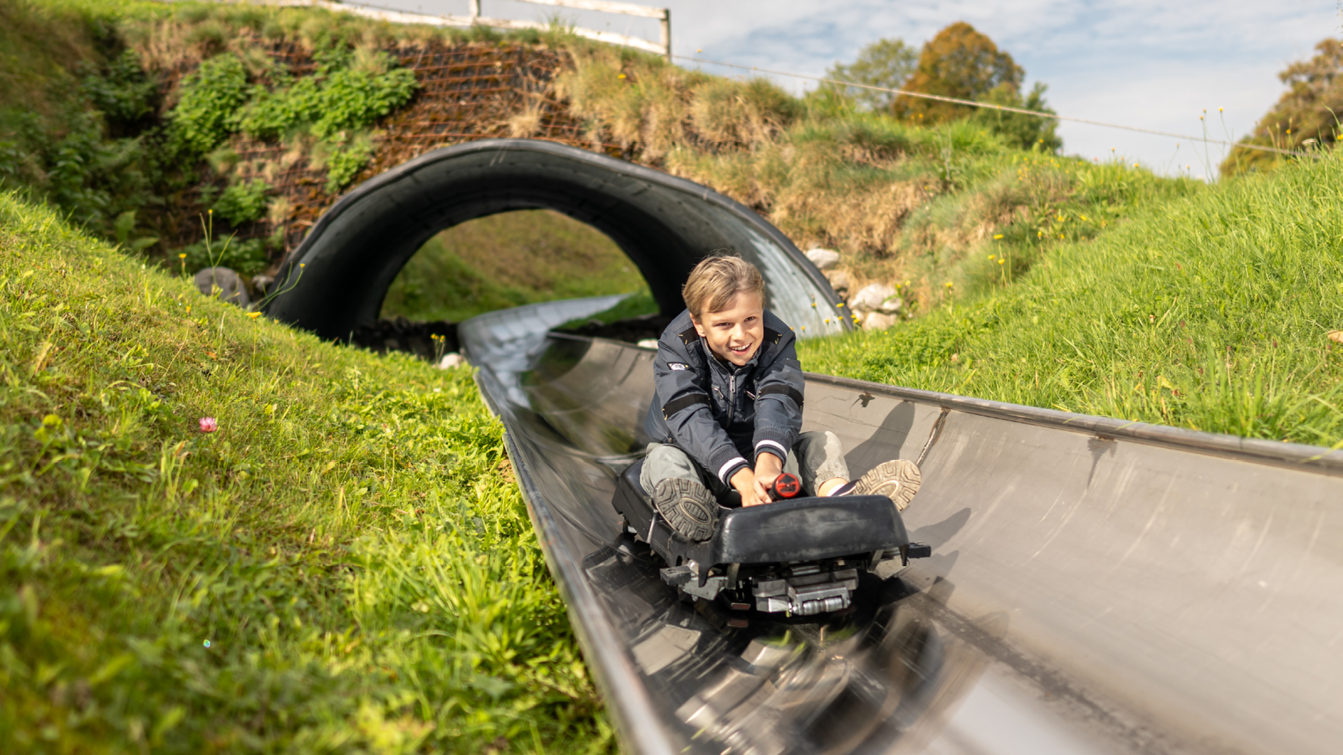 Junge kommt aus dem Tunnel der Rodelbahn