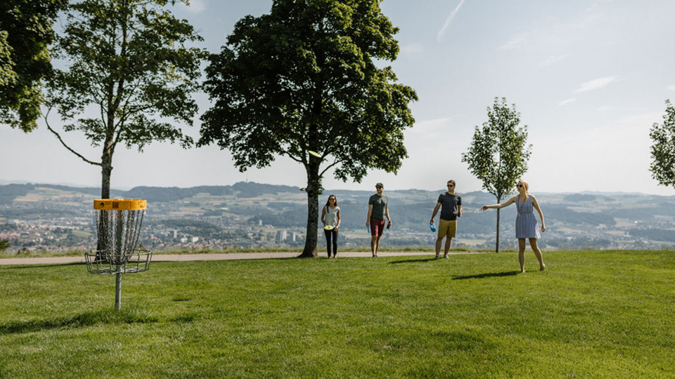 Eine Gruppe spielt Discgolf auf dem Gurten mit Aussicht auf die Stadt Bern