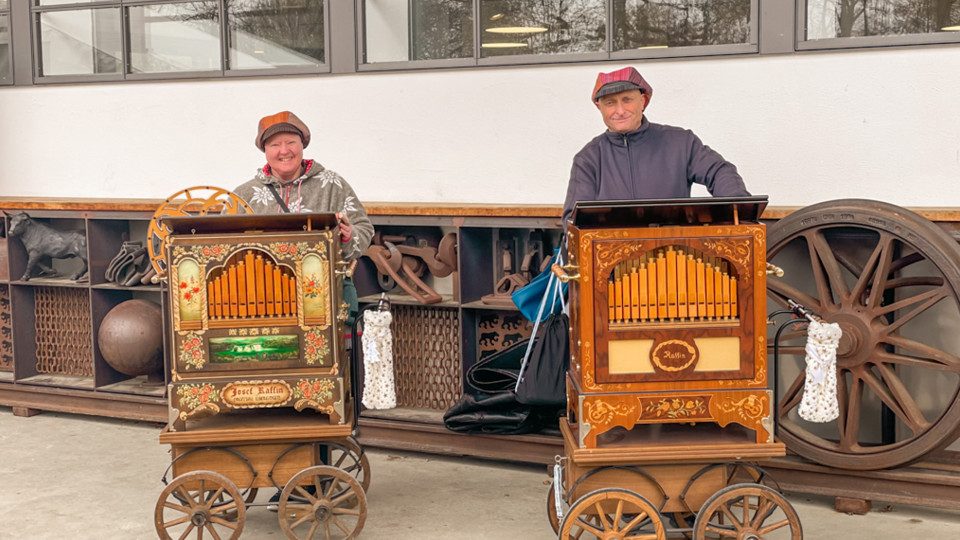Zwei Personen drehen an Drehorgeln.