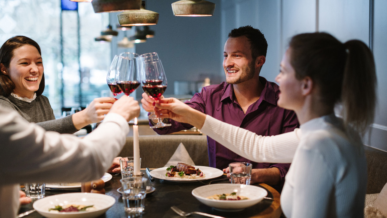 Vier Personen am Geniessermontag im Restaurant Gurtners welche gerade mit einem Glas Rotwein anstossen.