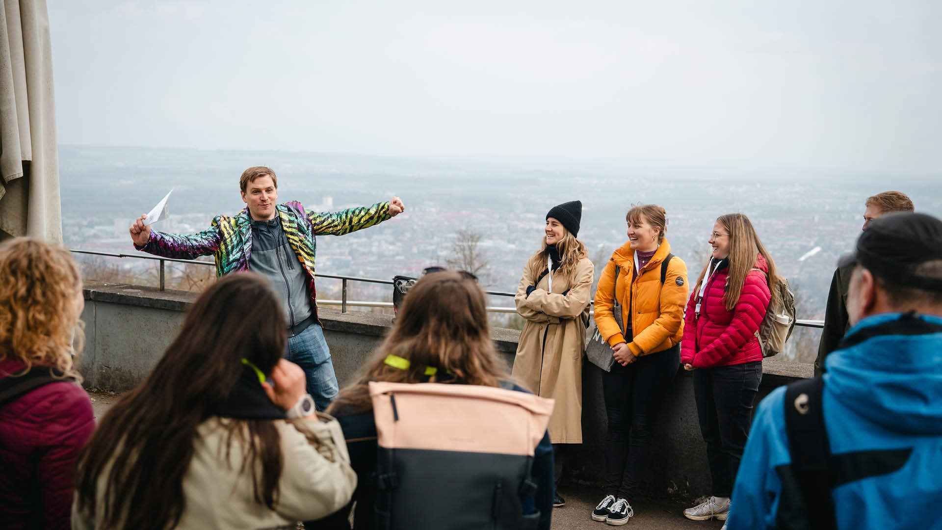 Mehrere Personen schauen einem Gruppenführer in einem farbigen Chaquet zu.