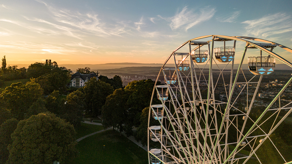 Das Riesenrad mit dem Kulm-Gebäude im Hintergrund bei Sonnenuntergang