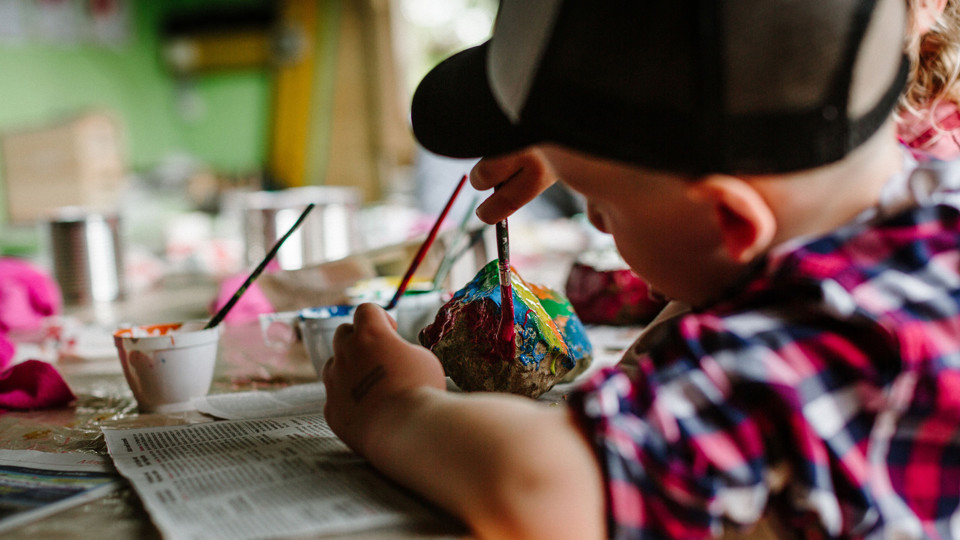 Ein kleines Kind welches ein Stein bemalt.