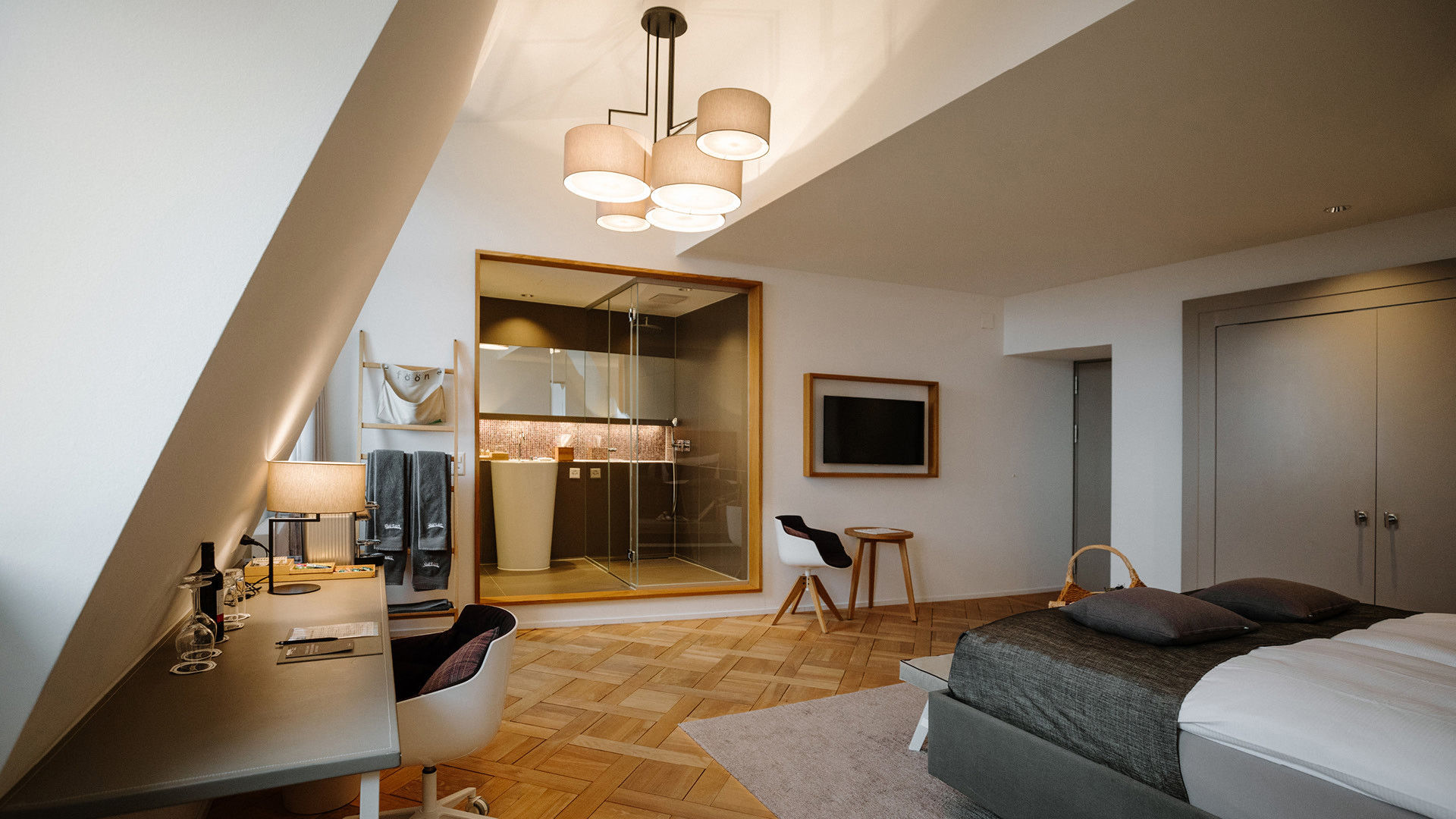 Ein Hotelzimmer mit einem grauen Teppich, einem grauen Schrank, zwei Handtüchern und Sicht auf das Badezimmer.