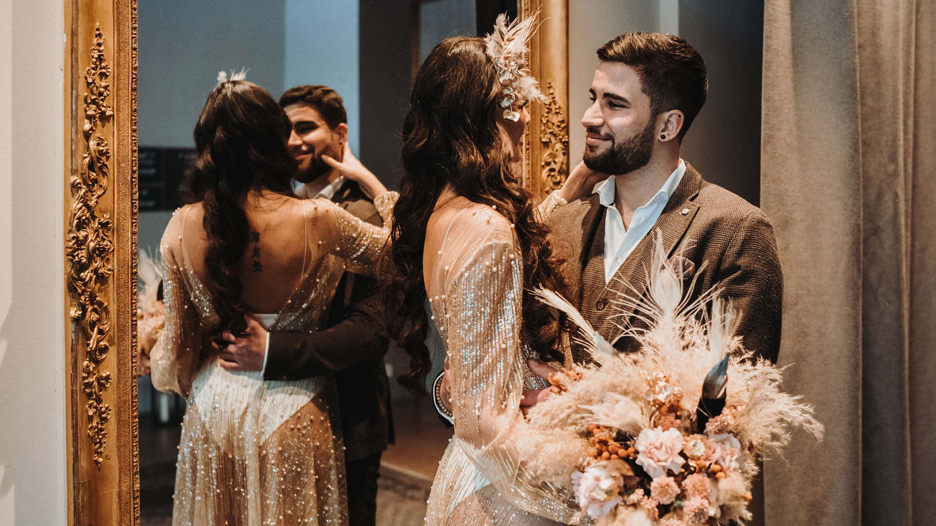Ein Hochzeitspaar schaut sich vor einem grossen Spiegel in die Augen.