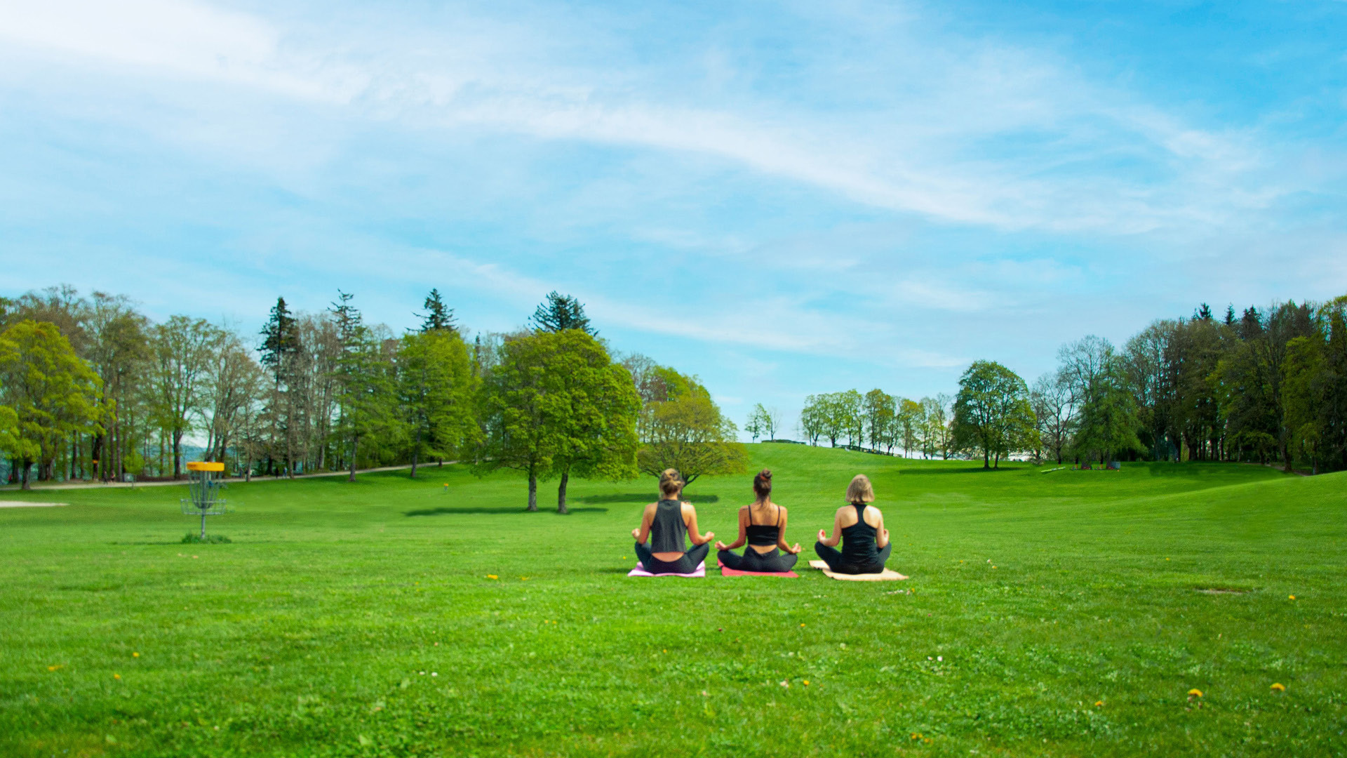 Drei Frauen machen Yoga auf der Gurtenwiese.